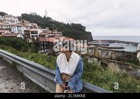 Donna seduta su una recinzione vicino al mare in Spagna Foto Stock