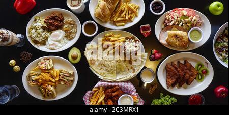 Inquadratura ad alto angolo di un tavolo con quesadillas, sandwich club, pane francese, baguette, Foto Stock