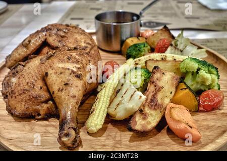 Pollo arrosto alla griglia e verdure assortite su un piatto di legno Foto Stock