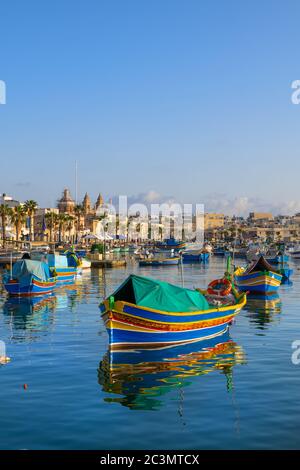 Le tradizionali barche di Luzzu maltesi nel porto del villaggio di pescatori di Marsaxlokk sull'isola di Malta nel Mar Mediterraneo Foto Stock