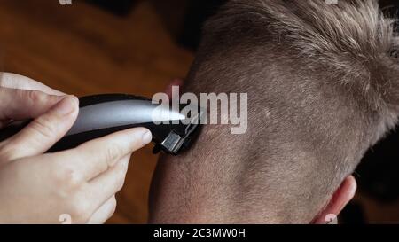 parrucchiere che taglia i capelli sul retro di una testina con un rifinitore. Foto Stock