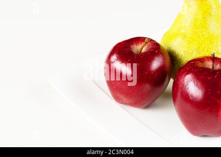 Mele rosse, pera verde in piatto bianco su tavola di legno bianca. Foto Stock