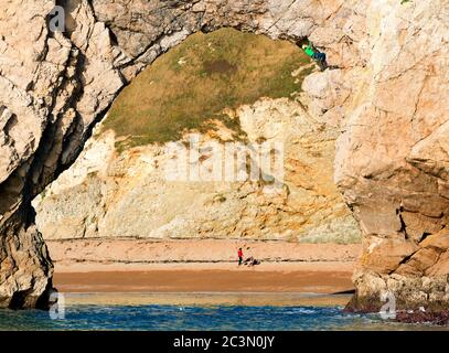 Un solista sull'arco di roccia di Durdle Door sulla Jurassic Coast a Dorset, Regno Unito, ritratto dall'offshore Foto Stock