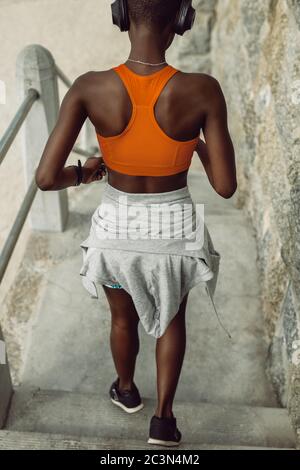 Vista posteriore di una donna che corre giù i gradini all'aperto. Giovane corridore femminile che lavora sui gradini . Foto Stock