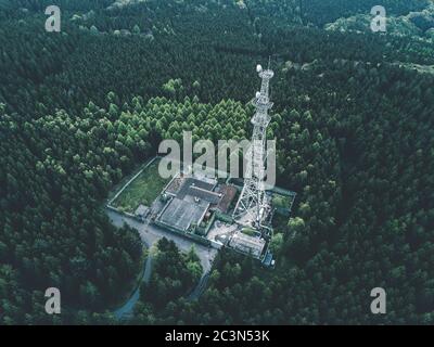 AEREO: Drone Shot della vecchia stazione radio Torre Abandones in ricca Foresta Verde circondata da alberi Foto Stock