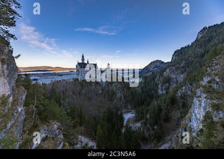 Vista mozzafiato del famoso castello di Neuschwanstein in una mattinata invernale dal Ponte di Maria, con cielo blu e il lago di Forggensee sullo sfondo, SCH Foto Stock