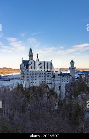 Vista mozzafiato sul famoso castello di Neuschwanstein la mattina d'inverno dal ponte Marien, con il sole e il lago Forggensee nel backgro Foto Stock