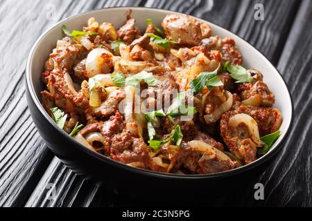 Fegato di pollo fritto, cuore e stomaci con cipolle, pomodori e spezie primo piano in una ciotola sul tavolo. Orizzontale Foto Stock