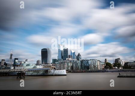 I moderni grattacieli della città di Londra visti dalla riva sud del Tamigi in una giornata estiva nuvolosa. Esposizione lunga. Foto Stock