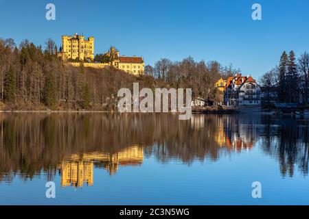 Vista mozzafiato sul lago Alpsee in inverno in una giornata di sole con il Castello di Hohenschwangau e le Alpi Bavaresi sullo sfondo, con bellissimi riflessi Foto Stock