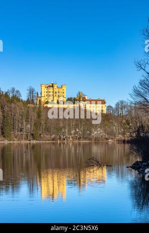 Vista mozzafiato sul lago Alpsee in inverno in una giornata di sole con il Castello di Hohenschwangau e le Alpi Bavaresi sullo sfondo, con bellissimi riflessi Foto Stock