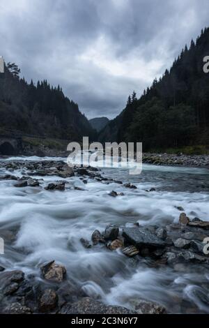 Fiume vicino cascata Latefossen a lunga esposizione in chiaro clima nuvoloso scuro. Acqua soffice e setosa nella valle di Odda, Norvegia. Verticale Foto Stock