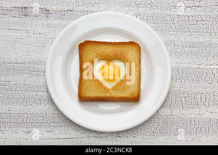 Uova in un buco di pane poi brindisi che anche conosciuto come uovo nel cestino. Foto Stock