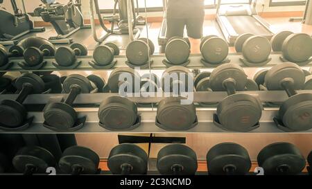 Set di manubri neri. Primo piano molti manubri in metallo su rack nel centro fitness sportivo, concetto di attrezzature per l'allenamento dei pesi. Foto Stock