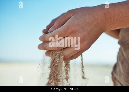 Far cadere la sabbia attraverso le mani di un bambino Foto Stock