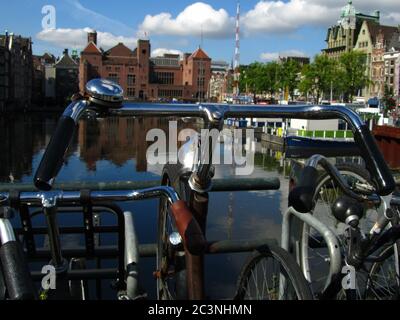 AMSTERDAM, PAESI BASSI - 22 luglio 2012: Una bicicletta con sterzo in metallo parcheggiata accanto ad un canale fluviale pieno d'acqua ad Amsterdam, Paesi Bassi durante il corso del s. Foto Stock