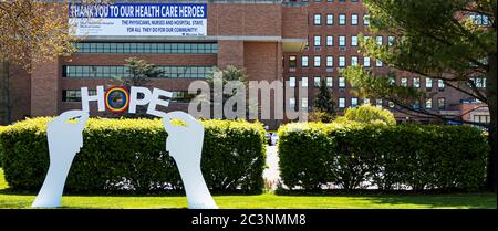 West Islip, New York, USA - 13 maggio 2020: Segno di mano in legno che tiene le parole SPERANZA posto di fronte al buon ospedale Samaritano durante il coronavirus Foto Stock