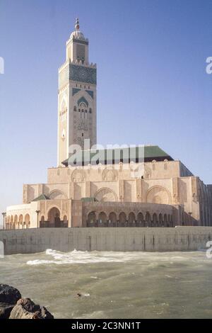 Un uomo che nuota nell'oceano di fronte alla moschea Hassan II a Casablanca, Marocco, durante un pomeriggio in autunno Foto Stock