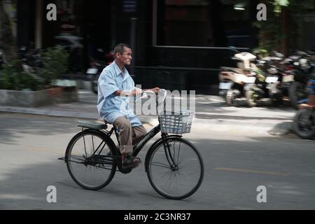 Un vecchio vietnamita che cavalcava la sua bicicletta sotto la luce del giorno. Ho Chi Minh City , Vietnam, 19 marzo 2017. Foto Stock