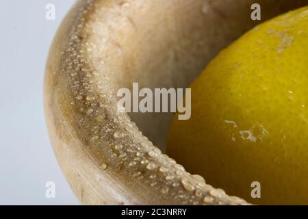 limone fresco in una ciotola di legno posta sulla destra, isolata su sfondo bianco Foto Stock