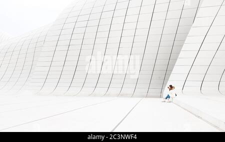 Baku, Azerbaigian - 01 gennaio 2018: Bella donna in bianco siede sulla parete bianca del Centro Aliev Heydar a Baku, Azerbaigian Foto Stock