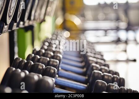 File di manubri in un club fitness sullo sfondo della palestra. Foto Stock