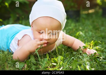 ritratto esterno di un bambino su tutte le farine. strisciando in ginocchio bambino sull'erba in un parco estivo. Foto Stock