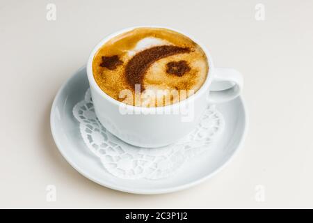 Una tazza bianca di cappuccino su un piatto bianco e un tovagliolo di carta. La crema di caffè è decorata con la luna alla cannella e le stelle. Foto Stock