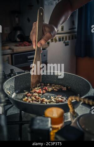 Colpo verticale di una mano che frittura carne tritata sul padella per friggere Foto Stock