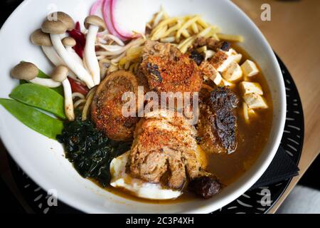 Delizioso ramen di chashu con maiale, uova, alghe, tagliatelle e funghi Foto Stock