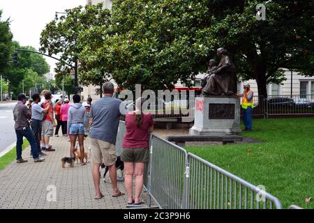 Raleigh, NC, Stati Uniti, 20 giugno 2020 - come una folla guarda i lavoratori separare la statua onorando le donne della Confederazione dalla sua base per la rimozione. La decisione è giunta la mattina dopo che i dimostranti Juneteicenteschi, scatenati dall'uccisione della polizia di George Floyd, riescono a tirare due figure fuori della vicina colonna del Memoriale Confederato alta 70 piedi. La mattina del 20 il governatore del NC ordinò che fosse rimosso dai terreni del vecchio palazzo del Campidoglio e altri due monumenti confederati. Foto Stock