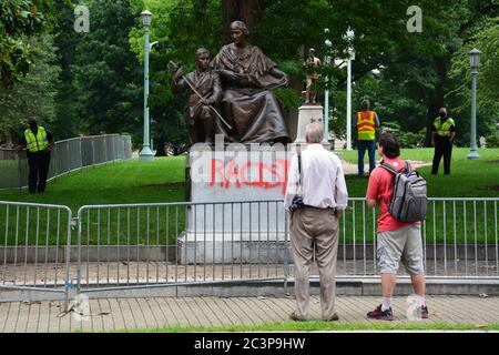 Raleigh, NC, Stati Uniti, 20 giugno 2020 - la gente si riunisce di fronte alla statua defaced che onora le donne della Confederazione mentre la parola si diffonde che sta venendo tolto. La decisione è giunta la mattina dopo che i dimostranti Juneteicenteschi, scatenati dall'uccisione della polizia di George Floyd, riescono a tirare due figure fuori della vicina colonna del Memoriale Confederato alta 70 piedi. La mattina del 20 il governatore del NC ordinò che fosse rimosso dai terreni del vecchio palazzo del Campidoglio e altri due monumenti confederati. Foto Stock