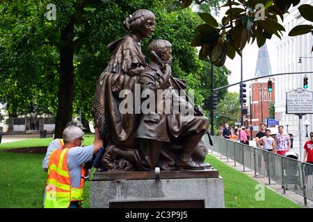 Raleigh, NC, Stati Uniti, 20 giugno 2020 - come una folla guarda i lavoratori separare la statua onorando le donne della Confederazione dalla sua base per la rimozione. La decisione è giunta la mattina dopo che i dimostranti Juneteicenteschi, scatenati dall'uccisione della polizia di George Floyd, riescono a tirare due figure fuori della vicina colonna del Memoriale Confederato alta 70 piedi. La mattina del 20 il governatore del NC ordinò che fosse rimosso dai terreni del vecchio palazzo del Campidoglio e altri due monumenti confederati. Foto Stock