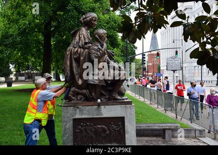 Raleigh, NC, Stati Uniti, 20 giugno 2020 - come una folla guarda i lavoratori separare la statua onorando le donne della Confederazione dalla sua base per la rimozione. La decisione è giunta la mattina dopo che i dimostranti Juneteicenteschi, scatenati dall'uccisione della polizia di George Floyd, riescono a tirare due figure fuori della vicina colonna del Memoriale Confederato alta 70 piedi. La mattina del 20 il governatore del NC ordinò che fosse rimosso dai terreni del vecchio palazzo del Campidoglio e altri due monumenti confederati. Foto Stock