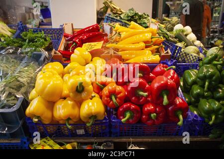 Colpo di primo piano di peperoni colorati in cestini blu su un scaffale di mercato Foto Stock