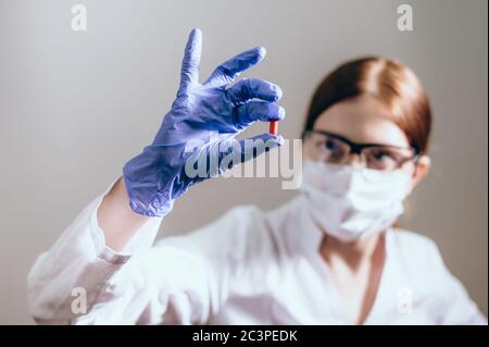 Scienziato femminile con maschera protettiva mostra una pillola di medicina. Concetto innovativo di trattamento. Il concetto di salute Foto Stock