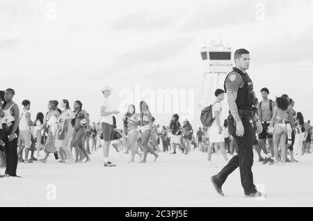 MIAMI - 15 MARZO 2019: Un poliziotto cammina attraverso folle di giovani che si riuniscono a South Beach per la vacanza annuale di primavera dalla scuola. Foto Stock