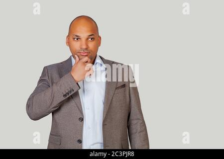 Un giovane afro-americano intelligente e fiducioso in tuta, tiene il mento e guarda attentamente al fianco, pensando al suo futuro. Foto Stock