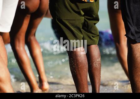 Un gruppo variegato di giovani che si godono la spiaggia in una luce solare dorata Foto Stock