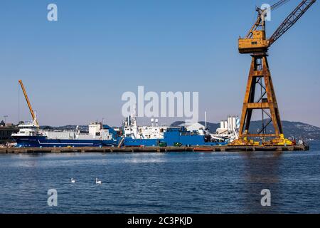 La grande gru a terra del vecchio cantiere navale BMV Laksevaag lungo Puddefjorden e Byfjorden nel porto di Bergen, Norvegia. In porto sono le navi Kommando Foto Stock