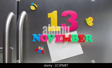 Novembre 13 data di calendario fatta con lettere magnetiche di plastica che tengono una nota di carta grafica sul frigorifero della porta Foto Stock