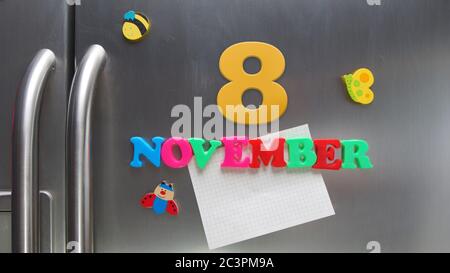 8 novembre data di calendario fatta con lettere magnetiche di plastica che tengono una nota di carta grafica sul frigorifero della porta Foto Stock