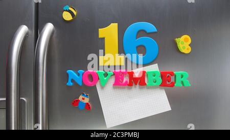 Novembre 16 data di calendario fatta con lettere magnetiche di plastica che tengono una nota di carta grafica sul frigorifero della porta Foto Stock