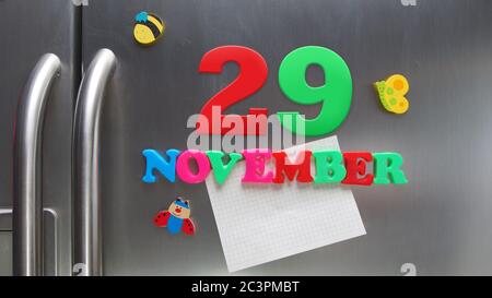 Novembre 29 data di calendario fatta con lettere magnetiche di plastica che tengono una nota di carta grafica sul frigorifero della porta Foto Stock