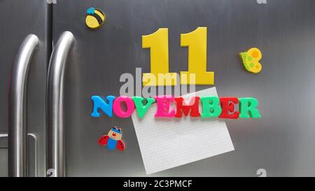 Novembre 11 data di calendario fatta con lettere magnetiche di plastica che tengono una nota di carta grafica sul frigorifero della porta Foto Stock