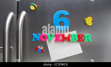 6 novembre data di calendario fatta con lettere magnetiche di plastica che tengono una nota di carta grafica sul frigorifero della porta Foto Stock