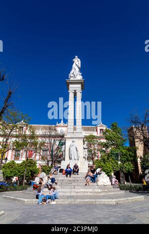 Turisti seduti al Monumento dell'Immacolata Concezione in Plaza del Triunfo, nel centro storico di Siviglia, Andalusia, Spagna Foto Stock