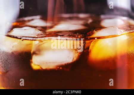 Cubetti di ghiaccio in un bicchiere di whisky o un altro alcool, primo piano. Foto Stock