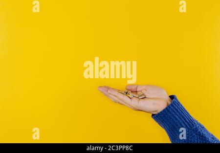 Capsule in una mano dell'uomo isolate su sfondo giallo Foto Stock