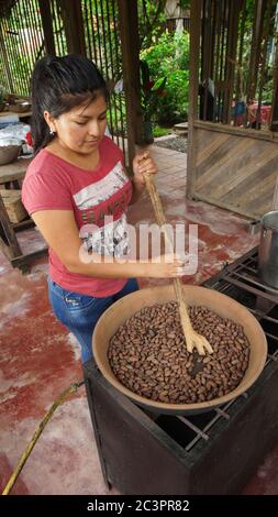 Puerto Quito, Pichincha / Ecuador - Agosto 17 2017: Giovane donna latina tostare fagioli cacao in una piccola cucina a gas. Tostare i semi di cacao fa parte della t Foto Stock